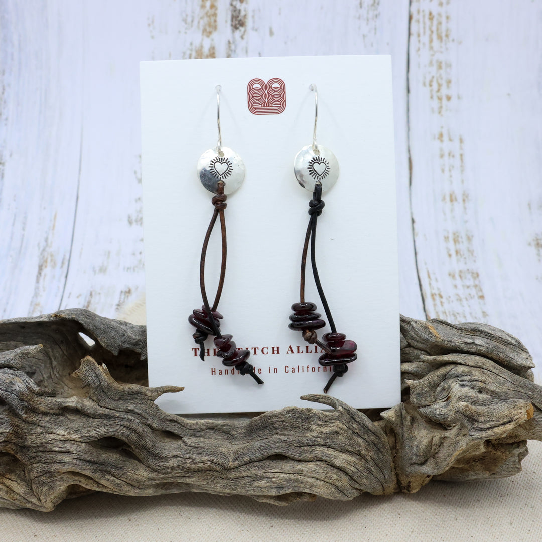 hand-stamped sacred heart sterling silver earrings with garnet beads on a white card