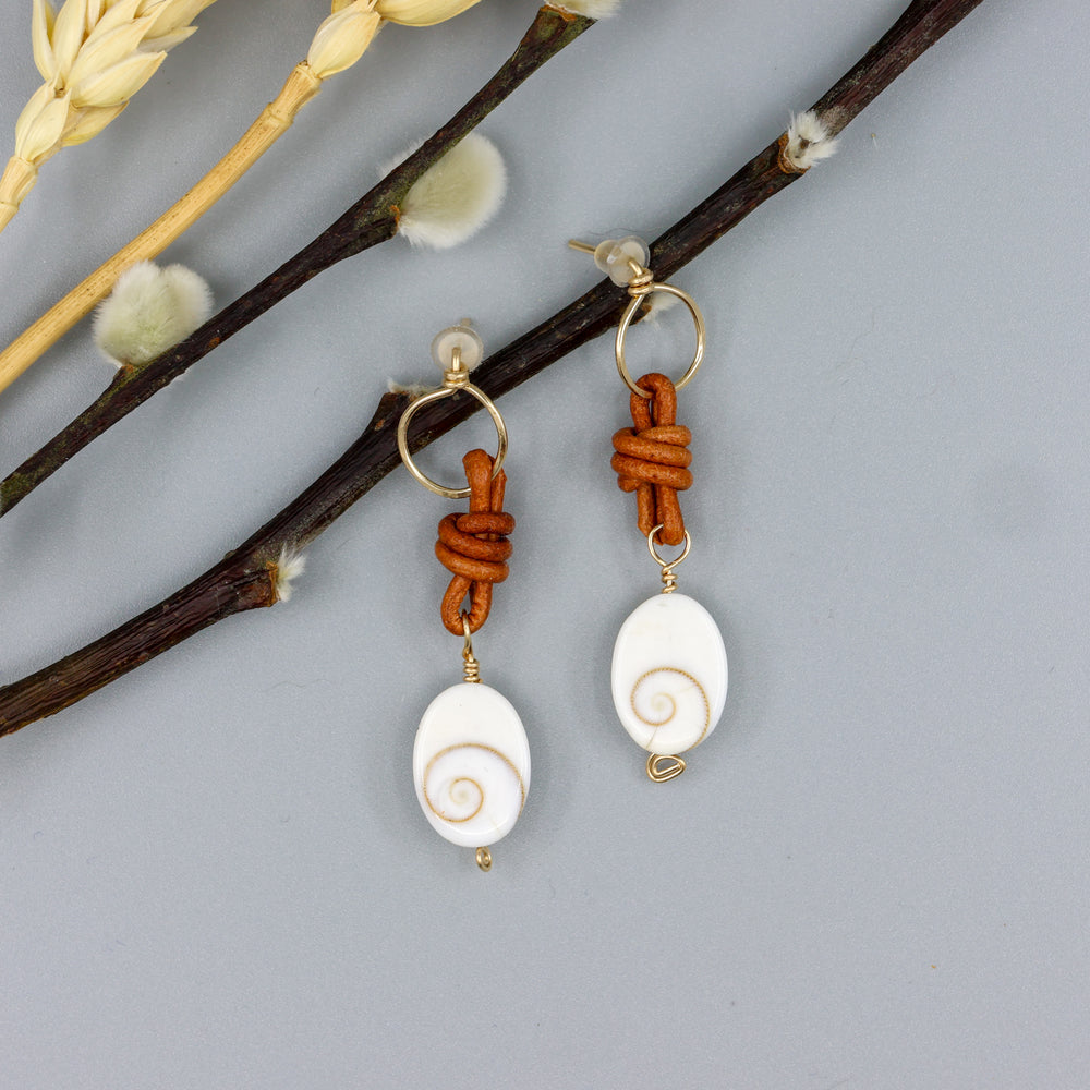 handmade shiva shell, leather, and gold fill drop earrings overhead view