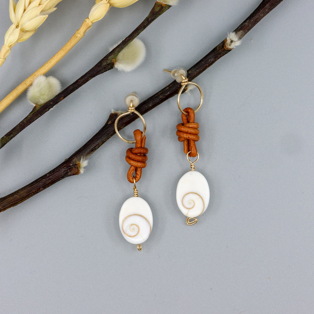 handmade shiva shell, leather, and gold fill drop earrings overhead view