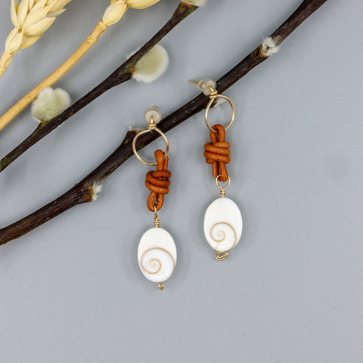 handmade shiva shell, leather, and gold fill drop earrings overhead view
