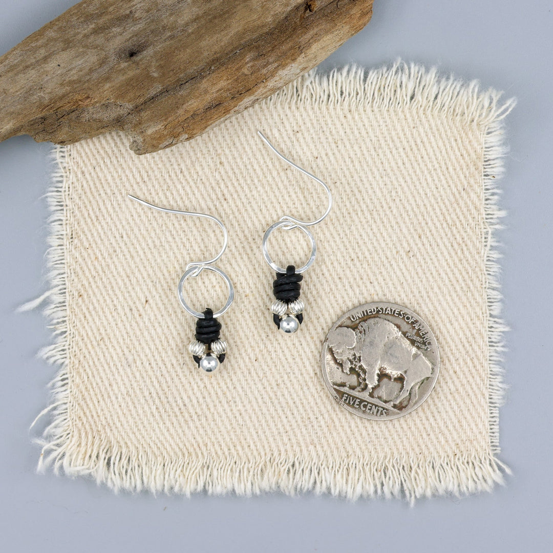 handmade sterling silver and leather knotted earrings with a nickel for size comparison
