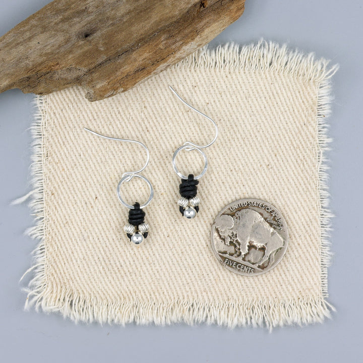 handmade sterling silver and leather knotted earrings with a nickel for size comparison