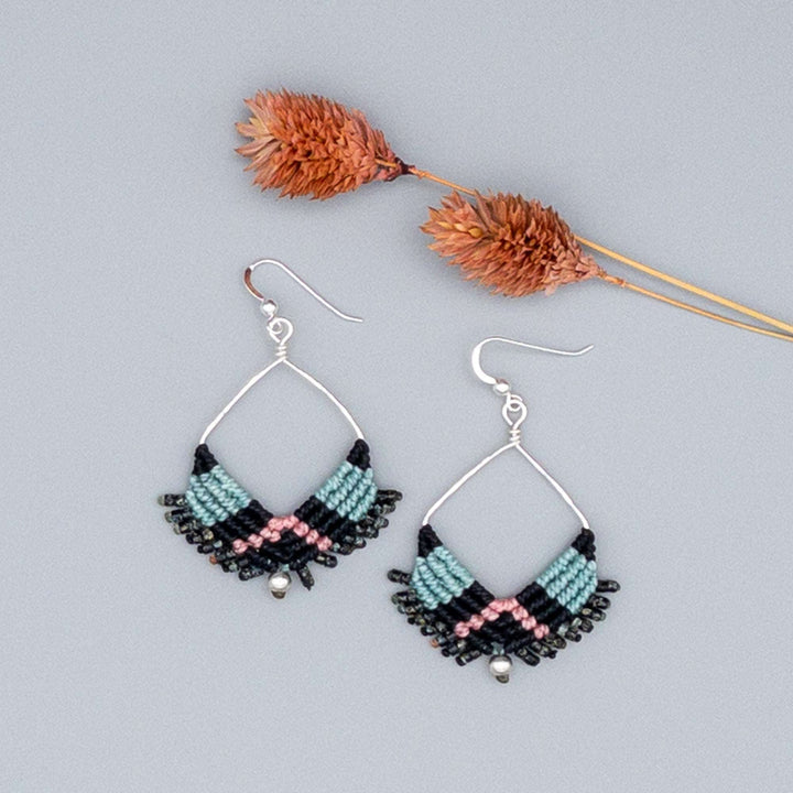 handmade macrame square hoop earrings in black, aqua, and pink with sterling silver wire on a gray background