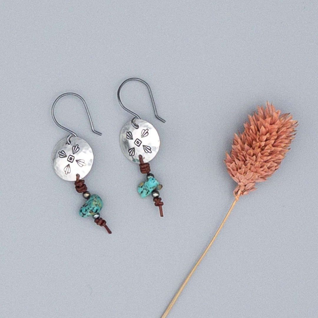 hand stamped sterling silver and turquoise drop earrings on gray background