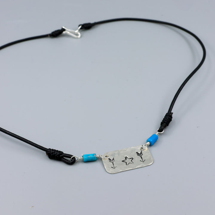 Handstamped star and arrow choker with turquoise beads on a gray background