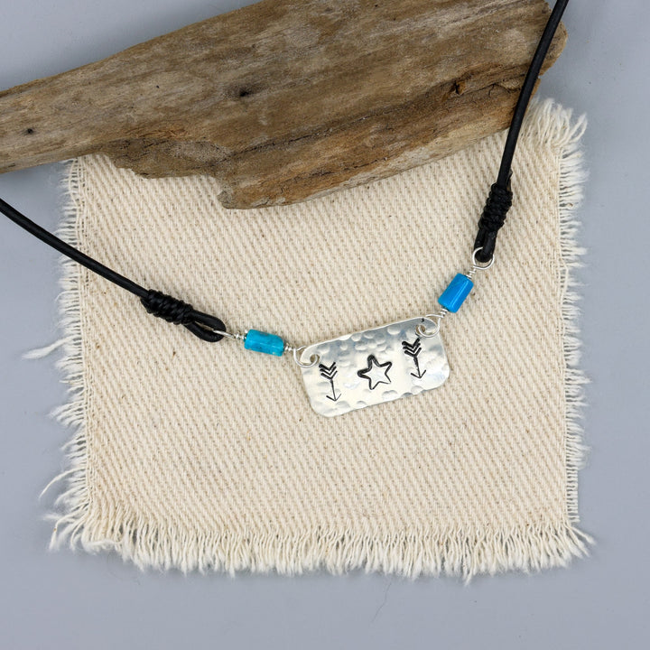 Handstamped star and arrow choker with turquoise beads on an off white background