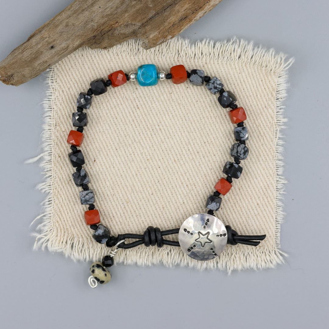handmade turquoise, jasper, and larvikite beaded bracelet with a star-stamped sterling silver button closure  an on off white background