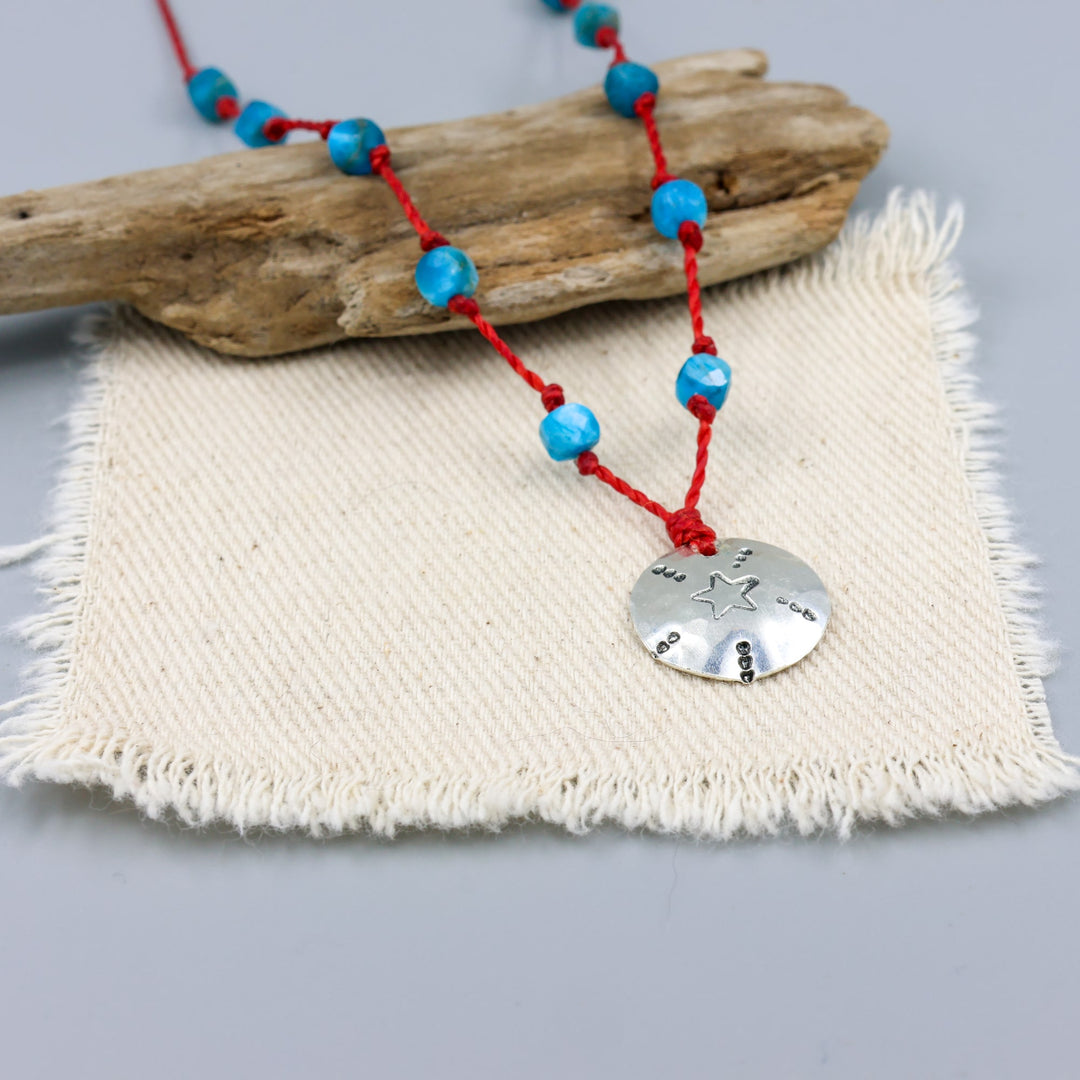 handmade silver stamped necklace with blue apatite beads on a red cord detail view