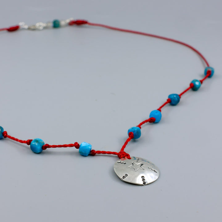 handmade silver stamped necklace with blue apatite beads on a red cord detail view