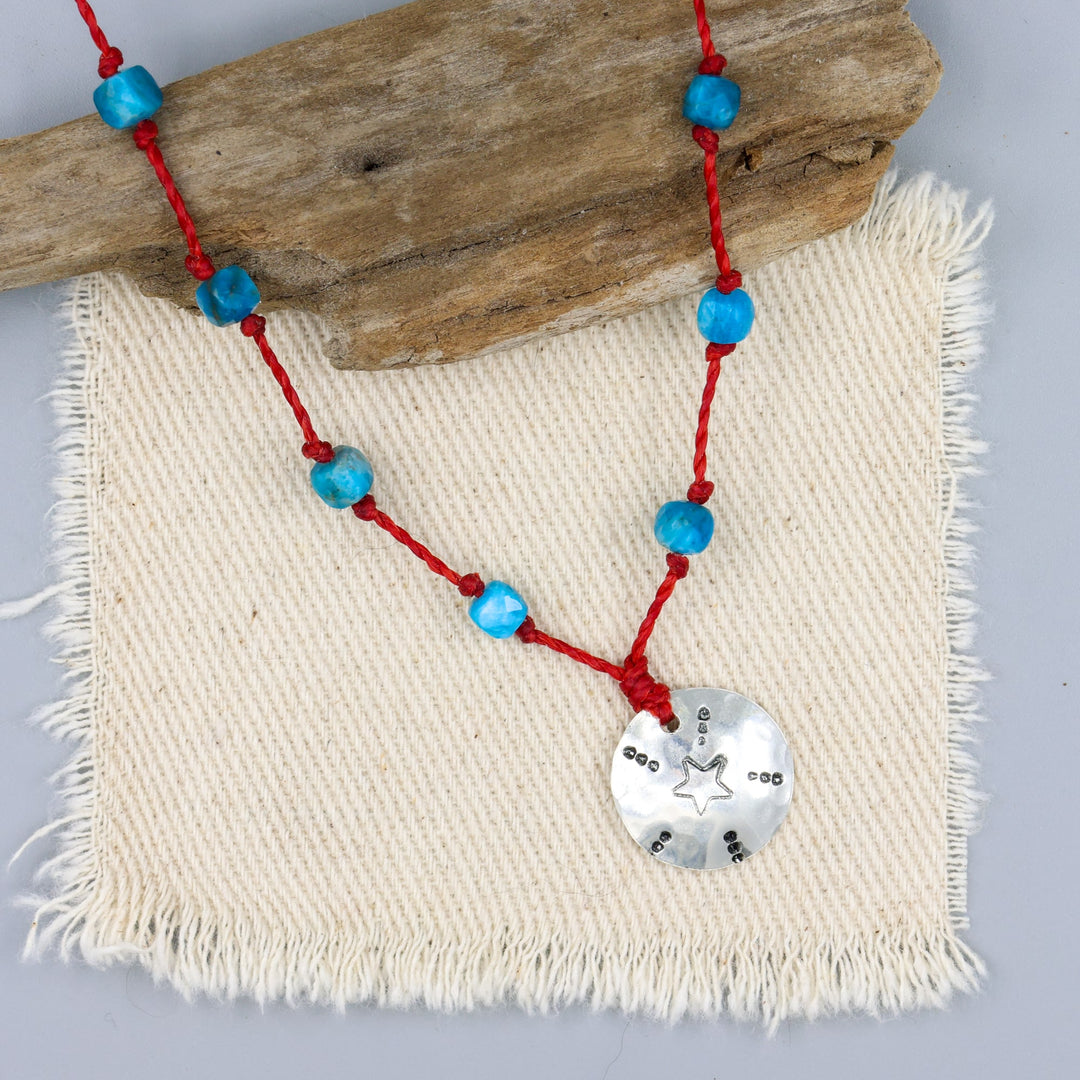 handmade silver stamped necklace with blue apatite beads on a red cord