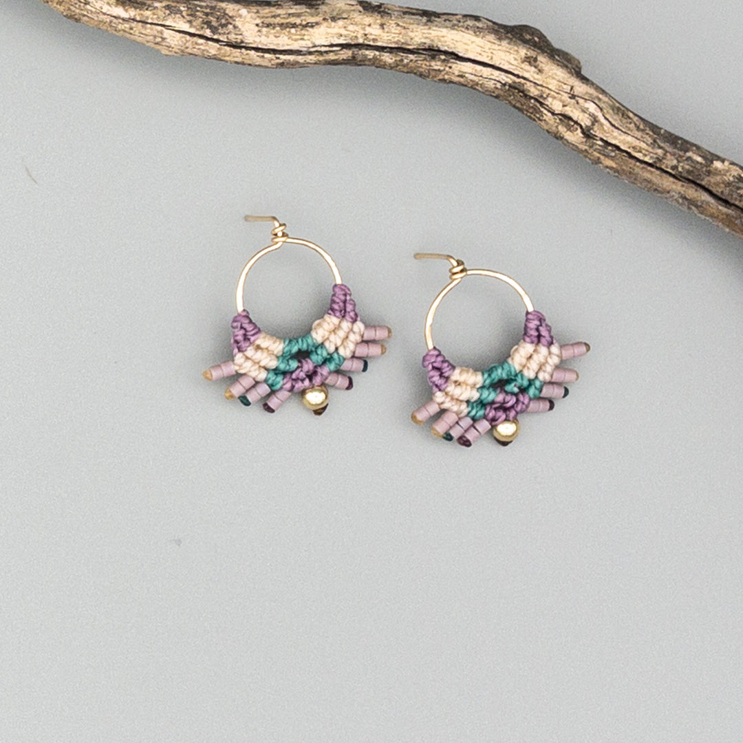 gold filled macrame earrings in green, purple, and natural on a gray background