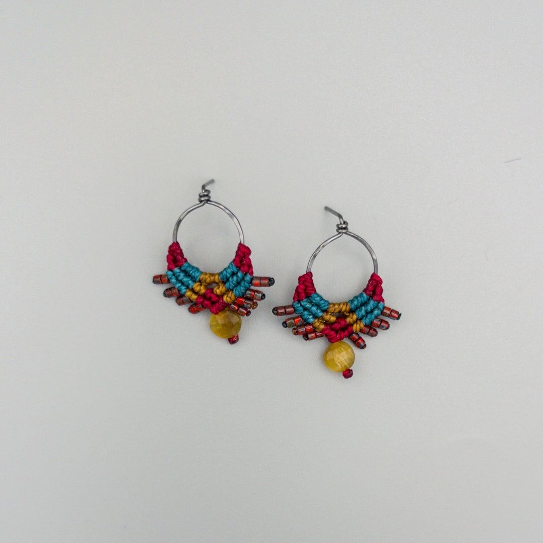 oxidized sterling silver macrame earrings in deep red, teal, and gold with golden tiger's eye bead on a gray background