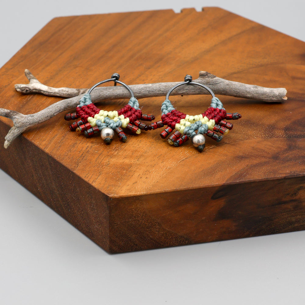 close up view of handmade macrame stud earrings in blue, deep red, and pale yellow with oxidized sterling silver metal