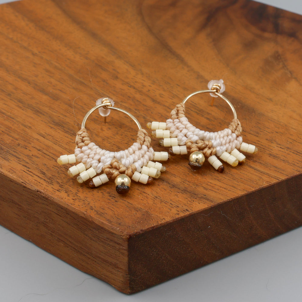 handmade macrame earrings with gold fill wire in tan colors on a wood display