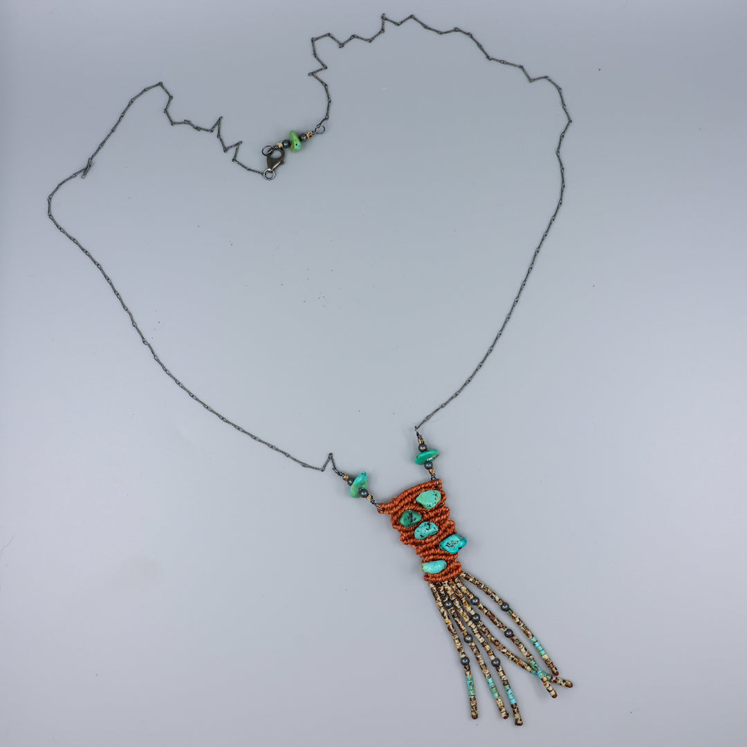 handmade macrame necklace with turquoise and seed beads on a gray background