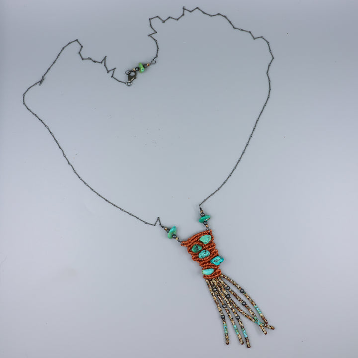 handmade macrame necklace with turquoise and seed beads on a gray background