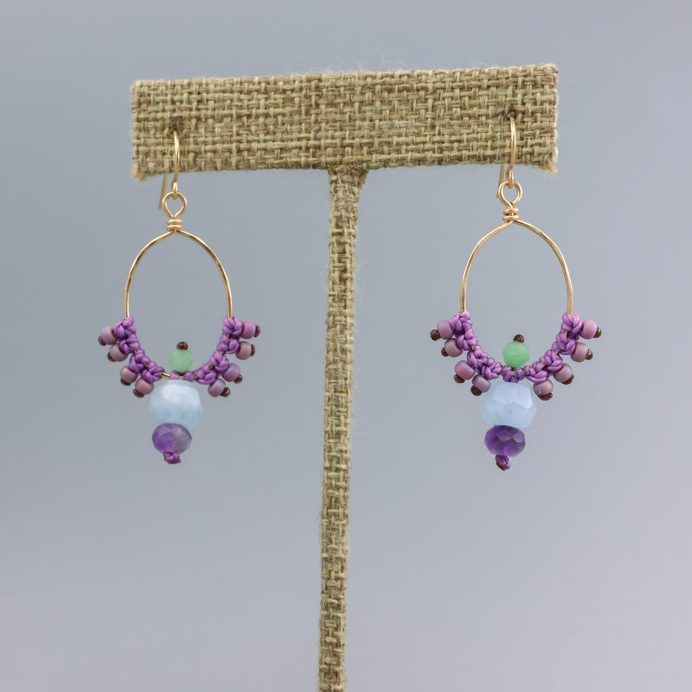 handmade, gold filled macrame hoops with aquamarine and amethyst beads on a linen hanger