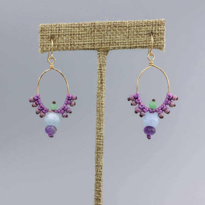 handmade, gold filled macrame hoops with aquamarine and amethyst beads on a linen hanger