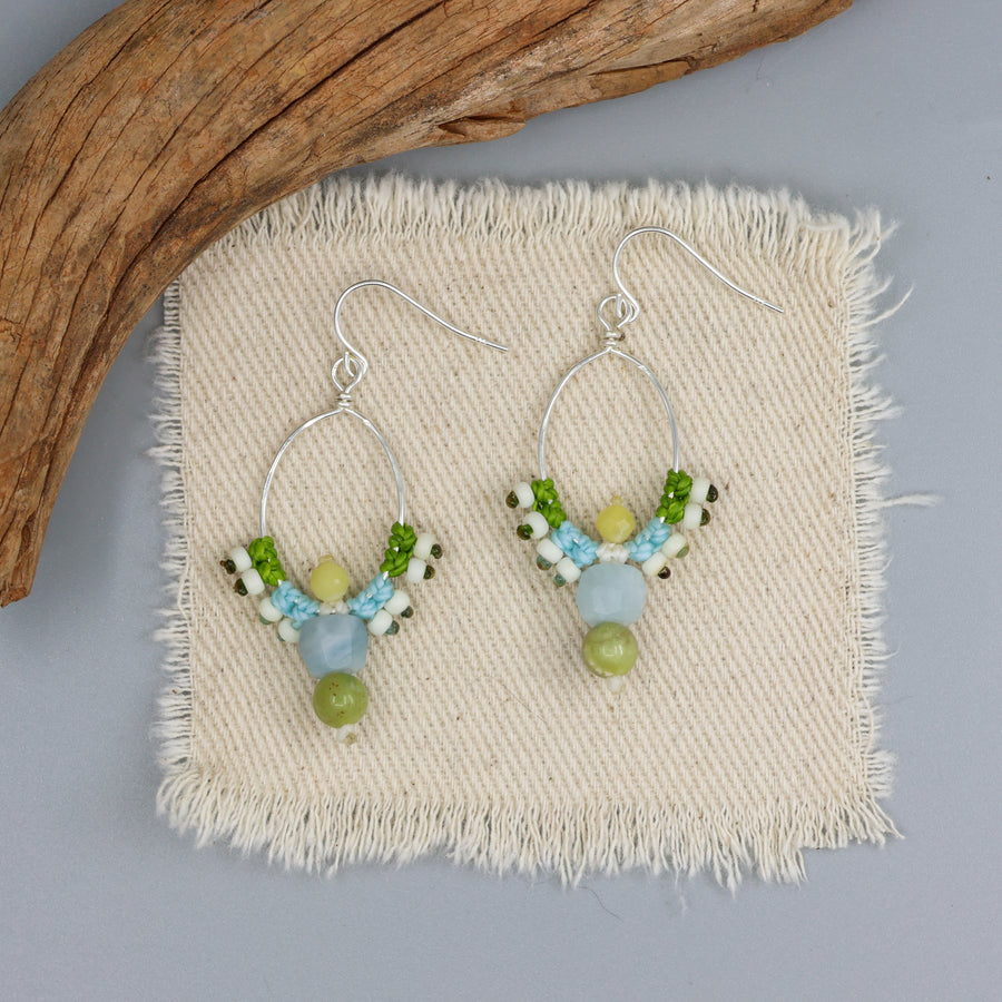 handmade macrame sterling hoop earrings with aquamarine, peridot, and yellow opal beads on an off white background