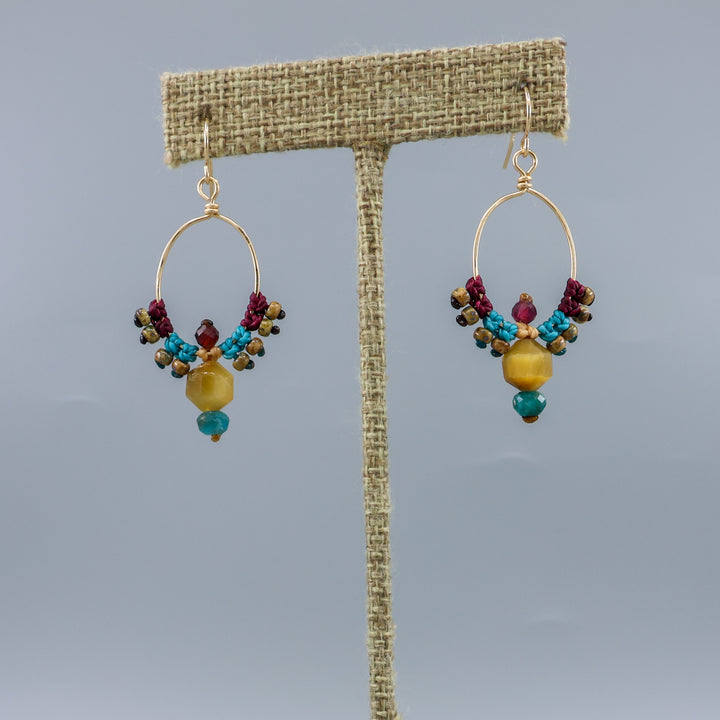 thunderbird inspired, 14k gold filled macrame hoop earrings with golden tiger's eye, blue apatite, and garnet beads on a linen hanger