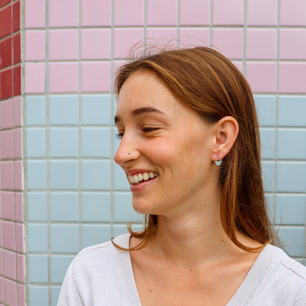 small triangle shaped sterling silver earrings with aquamarine beads worn on a model