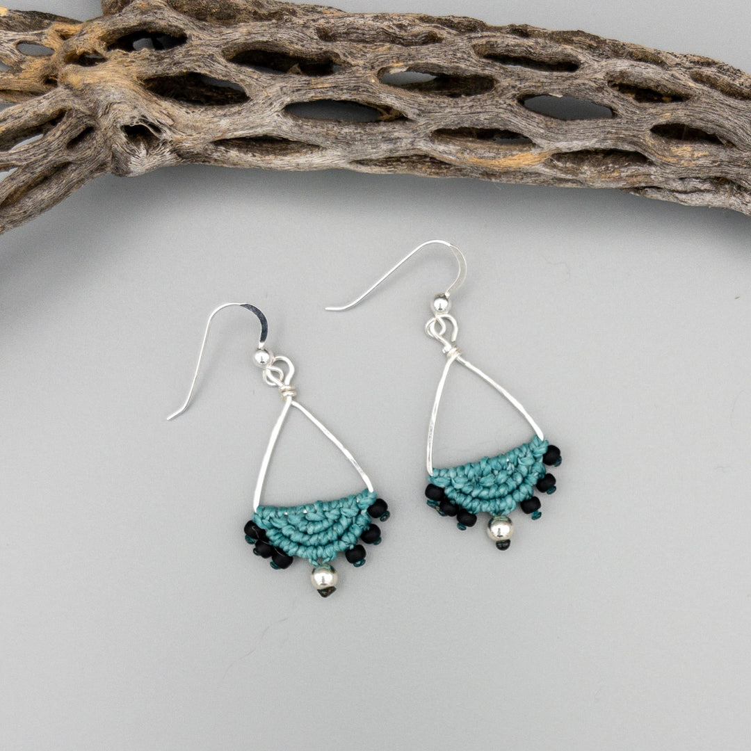 sterling silver triangle hoop macrame earrings in green on a gray background