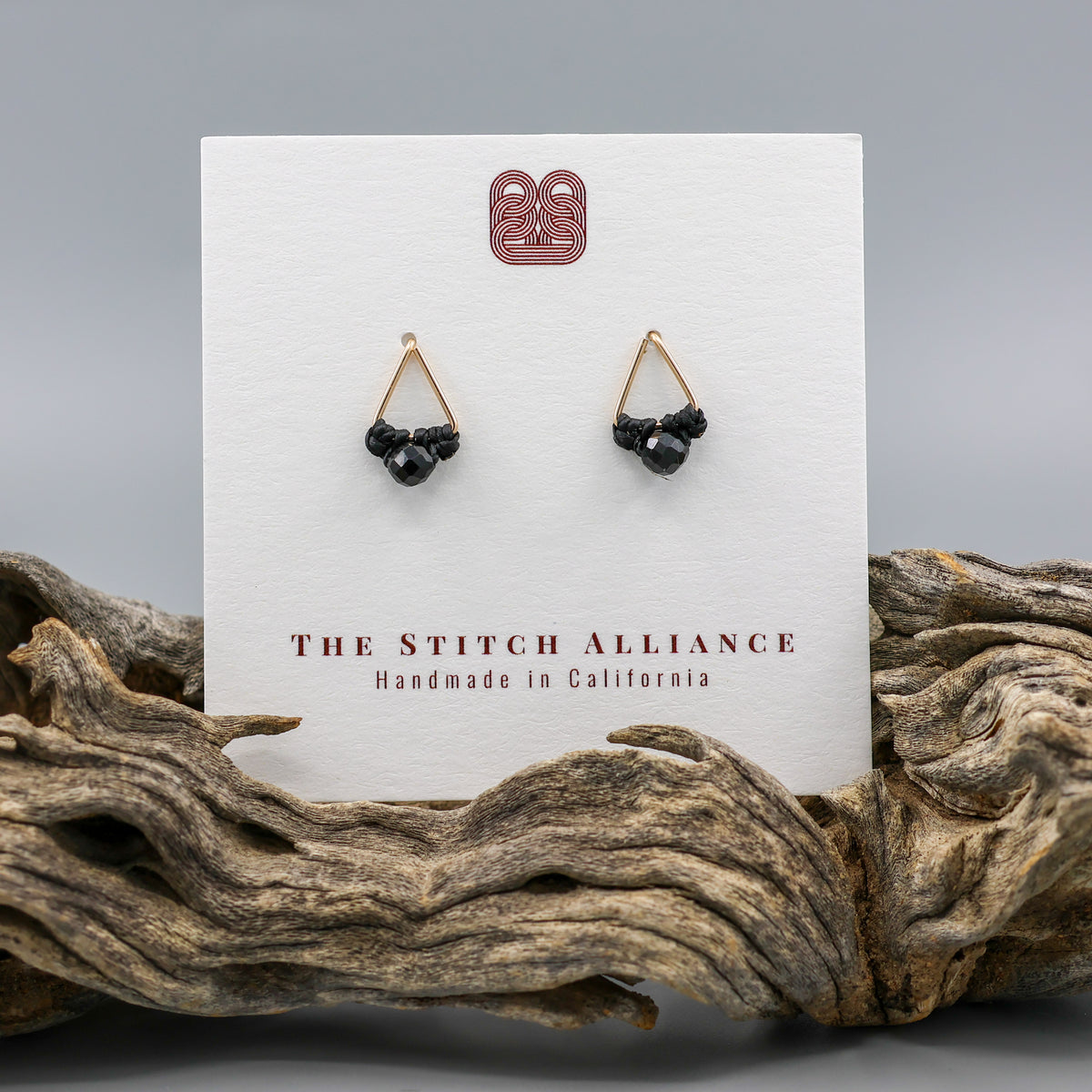 handmade triangle shaped earrings in gold fill with a black spinel bead on a white card