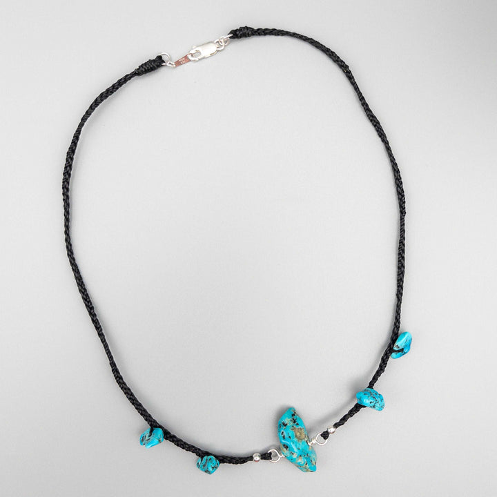 Turquoise choker necklace using vintage Kingman turquoise beads on a black plated cord and finished with sterling silver on a gray background.