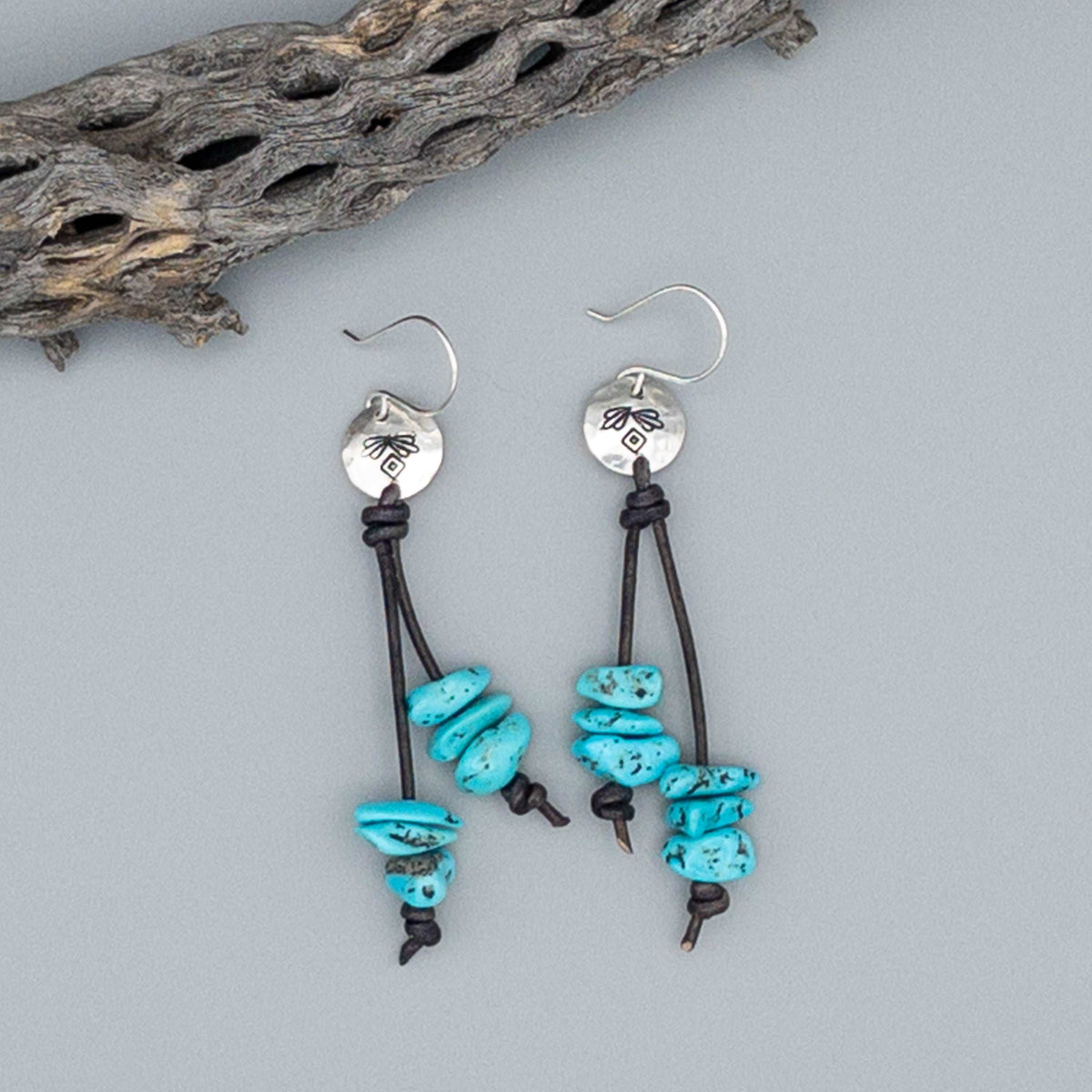Handmade turquoise bead sterling silver earrings on a gray background