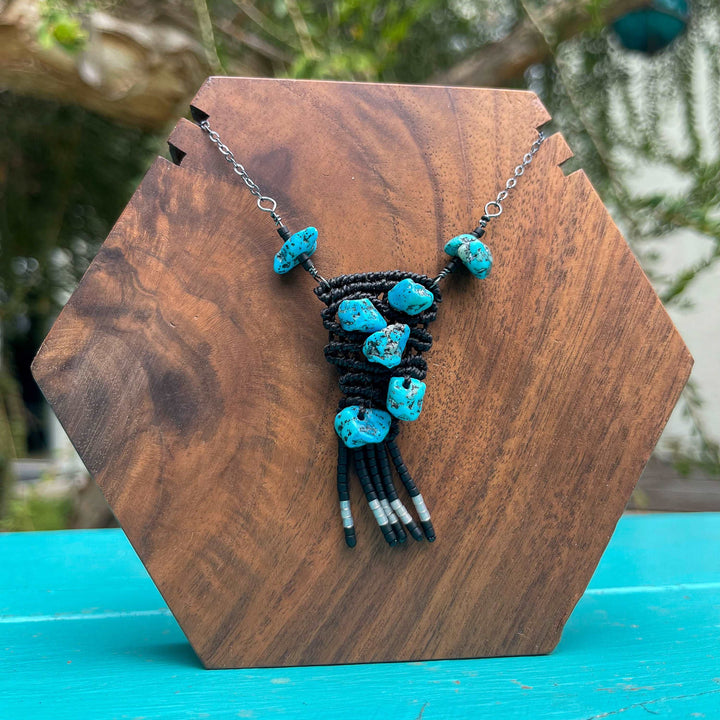 hand-woven macrame necklace with vintage kingman turquoise beads black with sterling silver chain shown on a wood block
