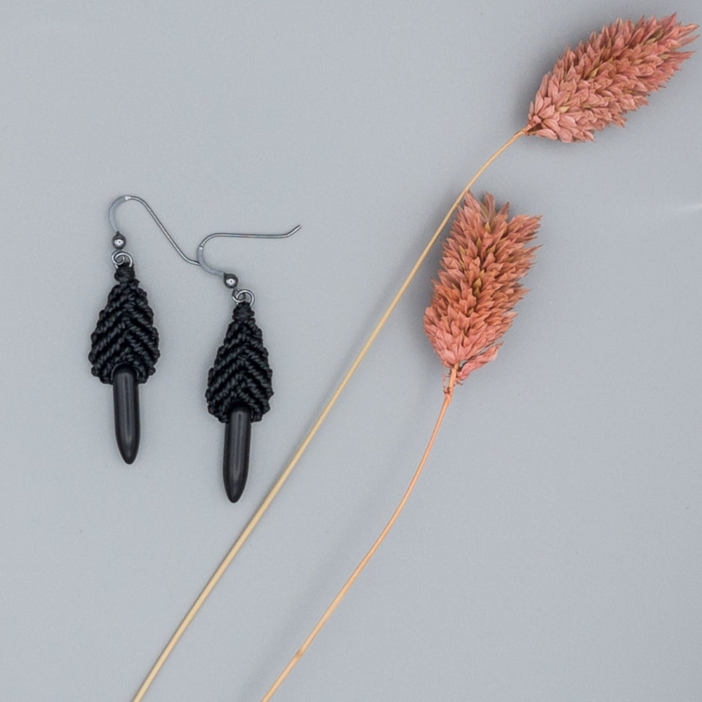 Close up of Black leaf shaped macrame earrings with oxidized sterling silver earring wires and spike-shaped black howlite beads
