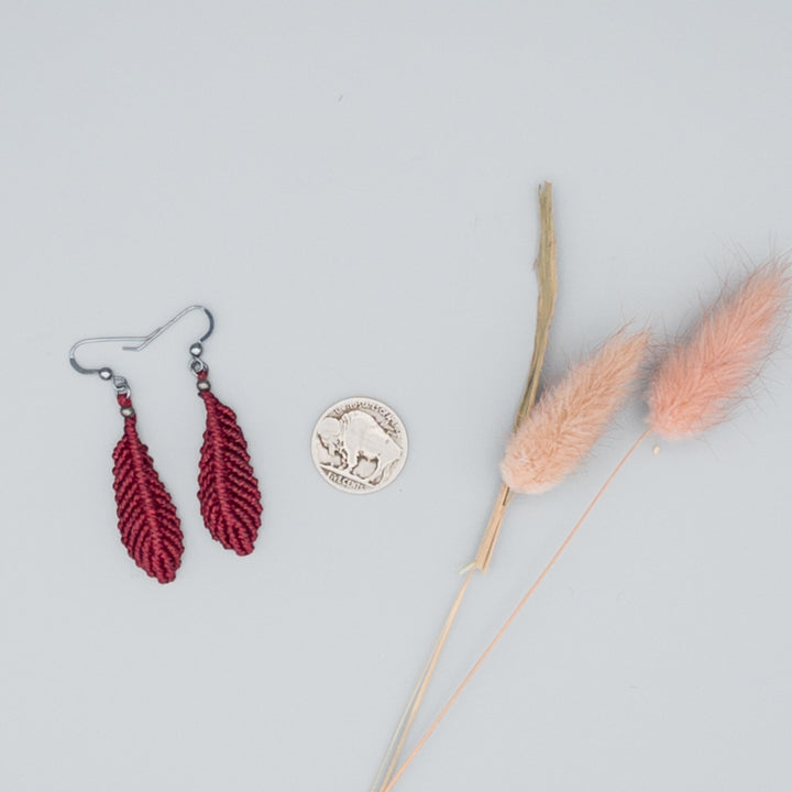 Deep red macrame feather earrings with oxidized sterling silver ear wires on gray background