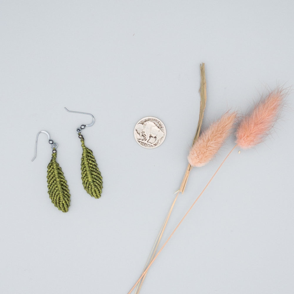 Olive green macrame feather earrings with oxidized sterling silver ear wires on gray background